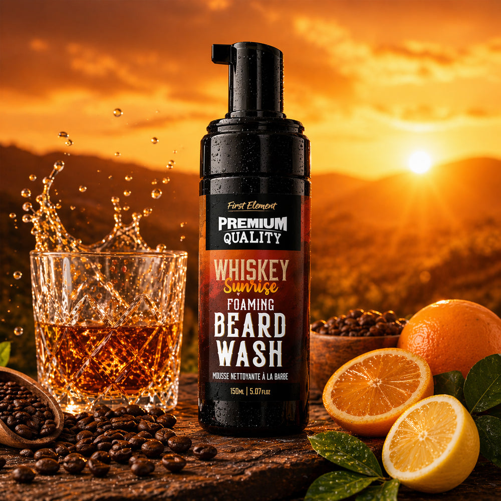 Foaming beard wash bottle labeled 'Whiskey Sunrise' with a glass of liquid, oranges, and lemons against a sunset background.