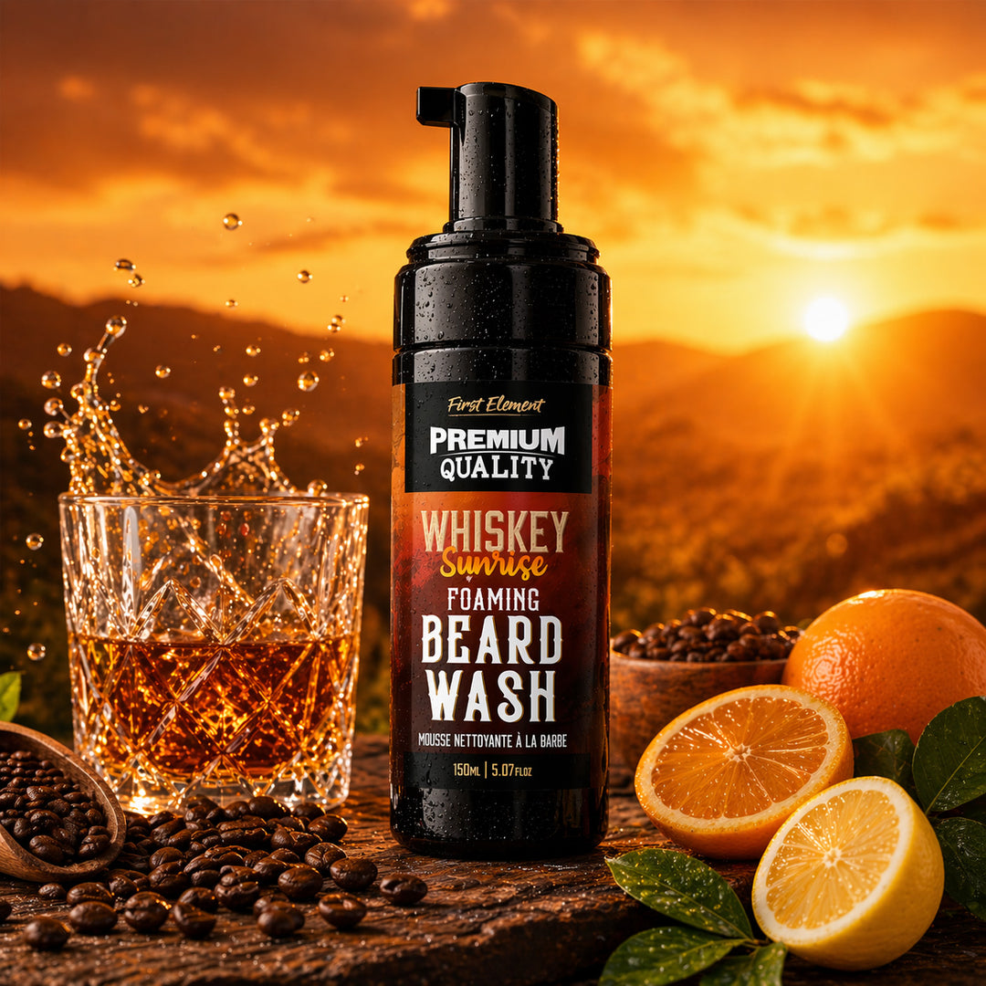 Foaming beard wash bottle labeled 'Whiskey Sunrise' with a glass of liquid, oranges, and lemons against a sunset background.