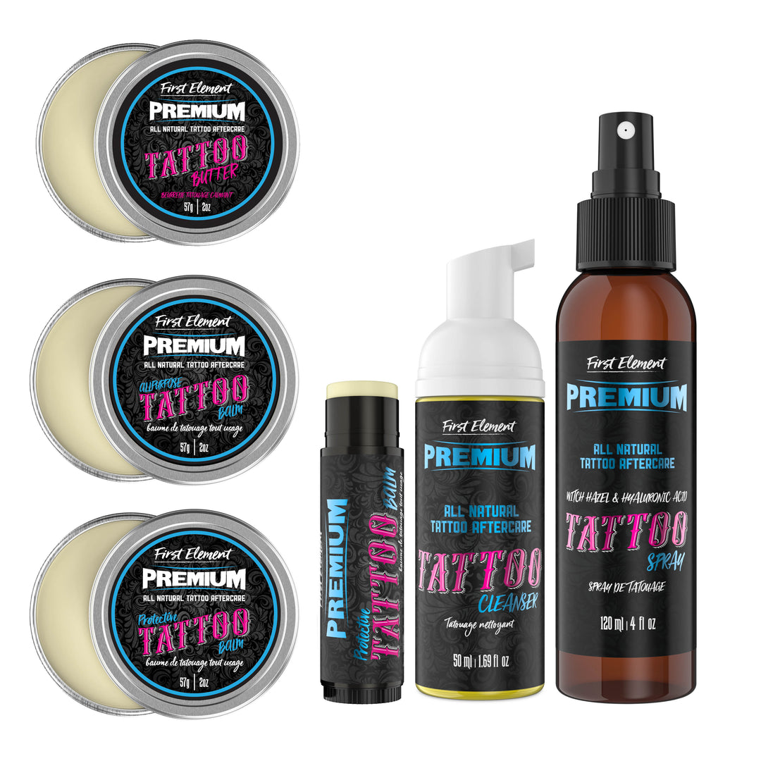 Five containers of tattoo aftercare products lined up neatly on a white background. The containers include Protective Tattoo Balm (2oz), All-Purpose Tattoo Balm (2oz), Tattoo Balm 15g Tube, Tattoo Butter (2oz), and Tattoo Cleanser 50g Foamer.