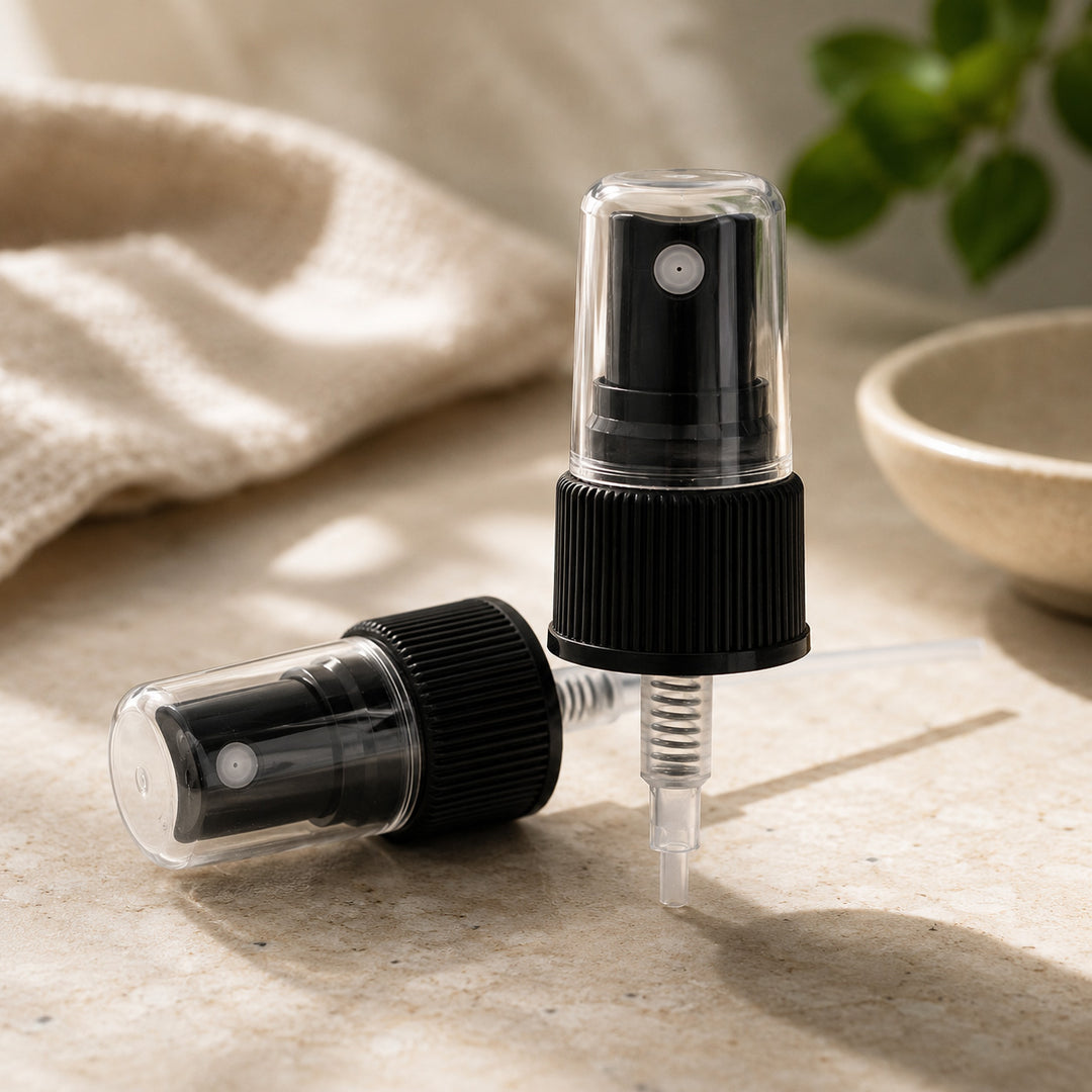 Two black fine mist sprayer lids with clear nozzles on a light surface.
