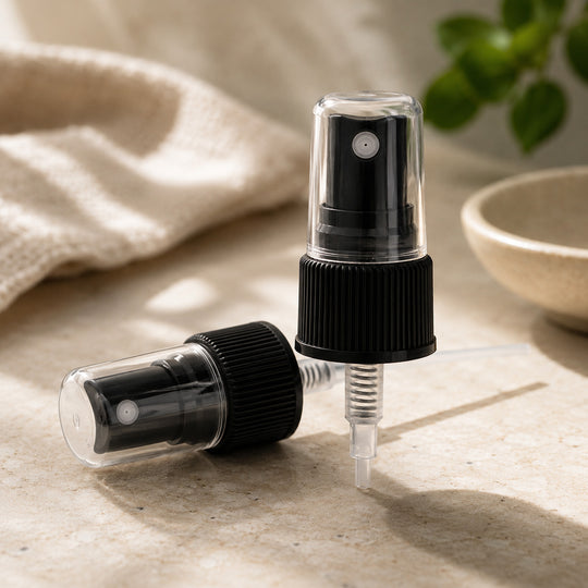 Two black fine mist sprayer lids with clear nozzles on a light surface.