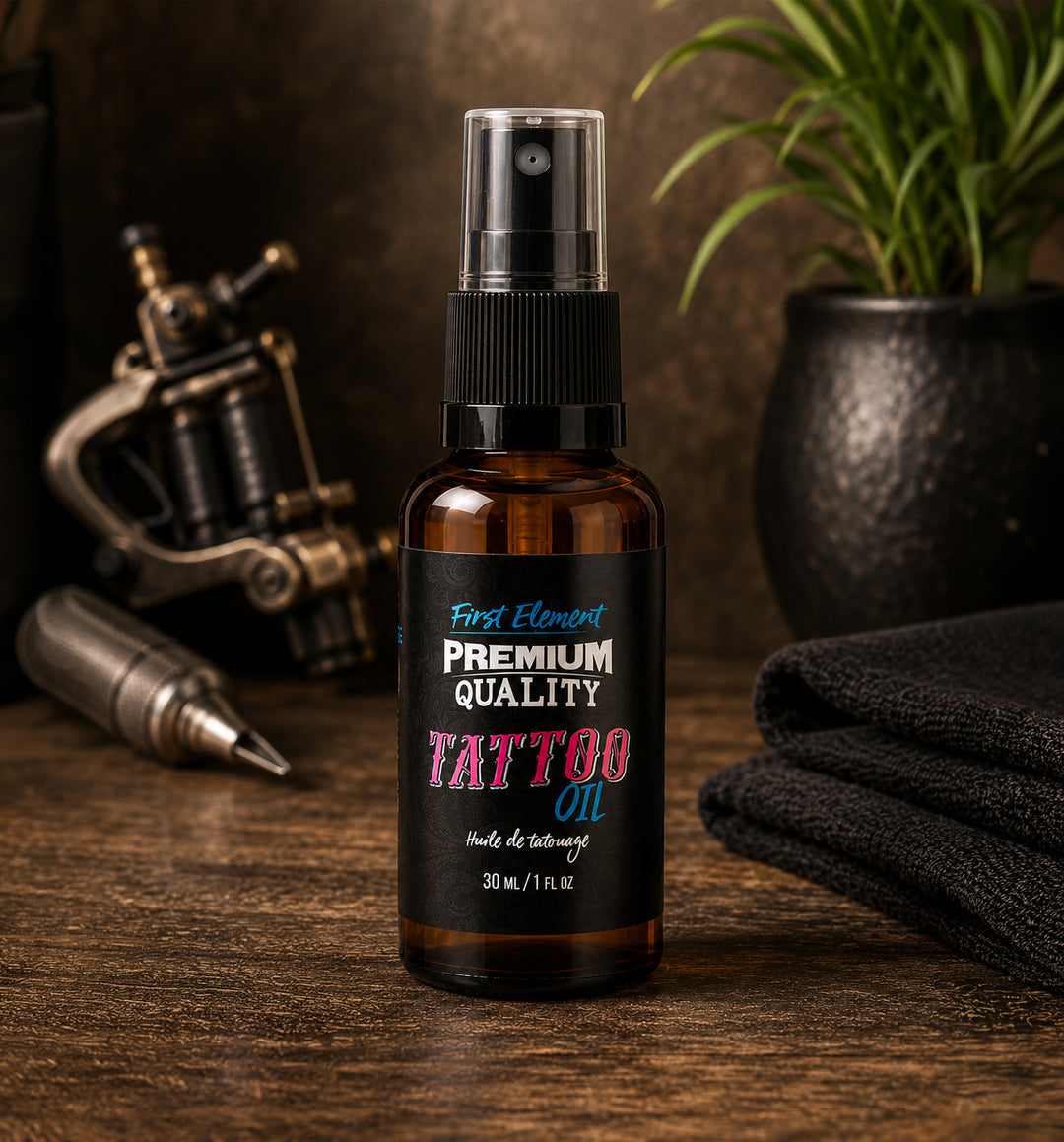 Bottle of tattoo oil with a black label on a wooden surface, surrounded by tattoo equipment.