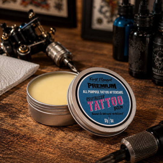 Tattoo balm in a metal tin with a blue label on a wooden surface with tattoo equipment.