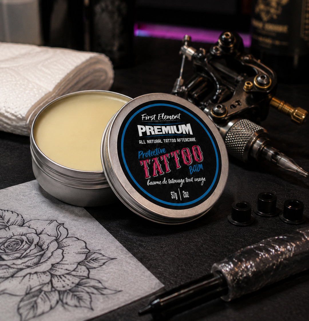 Tin of tattoo balm with tattoo equipment on a dark surface